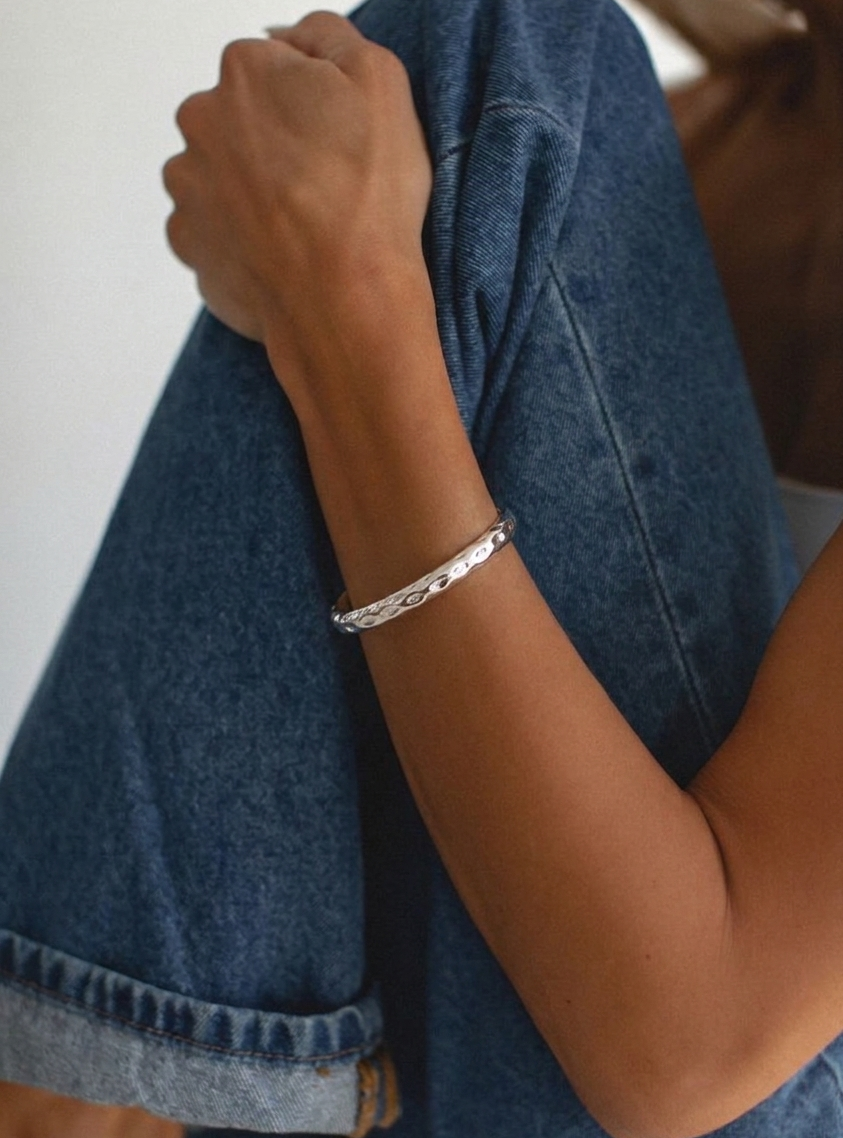 Person wearing a silver bracelet with a plain background