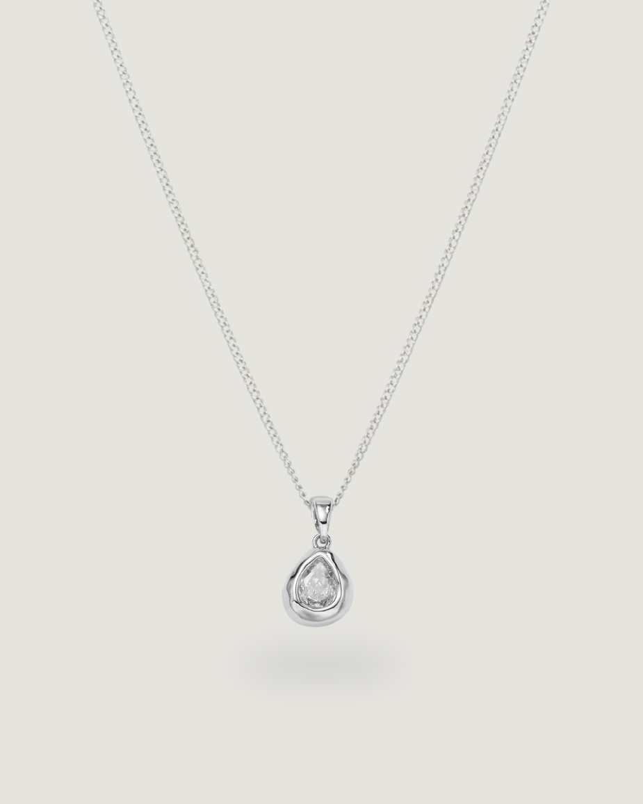 A delicate silver chain necklace with a small teardrop-shaped pendant set with a clear gemstone, displayed against a solid light gray background.