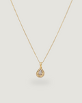 A delicate gold chain necklace with a teardrop-shaped pendant featuring a clear gemstone in a gold bezel setting, displayed against a solid light gray background.