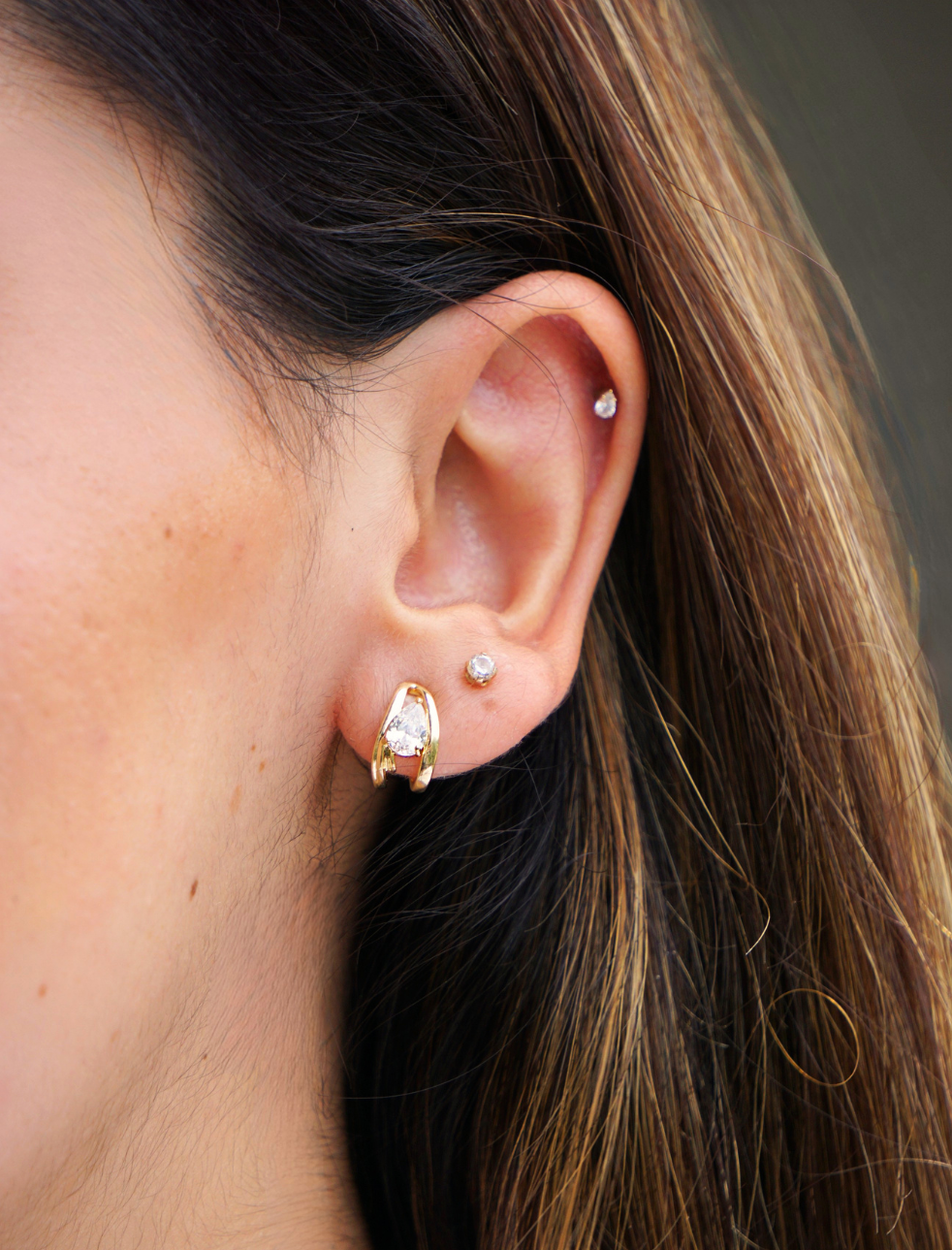 A pair of polished silver-tone abstract wavy hoop earrings on a light beige background.