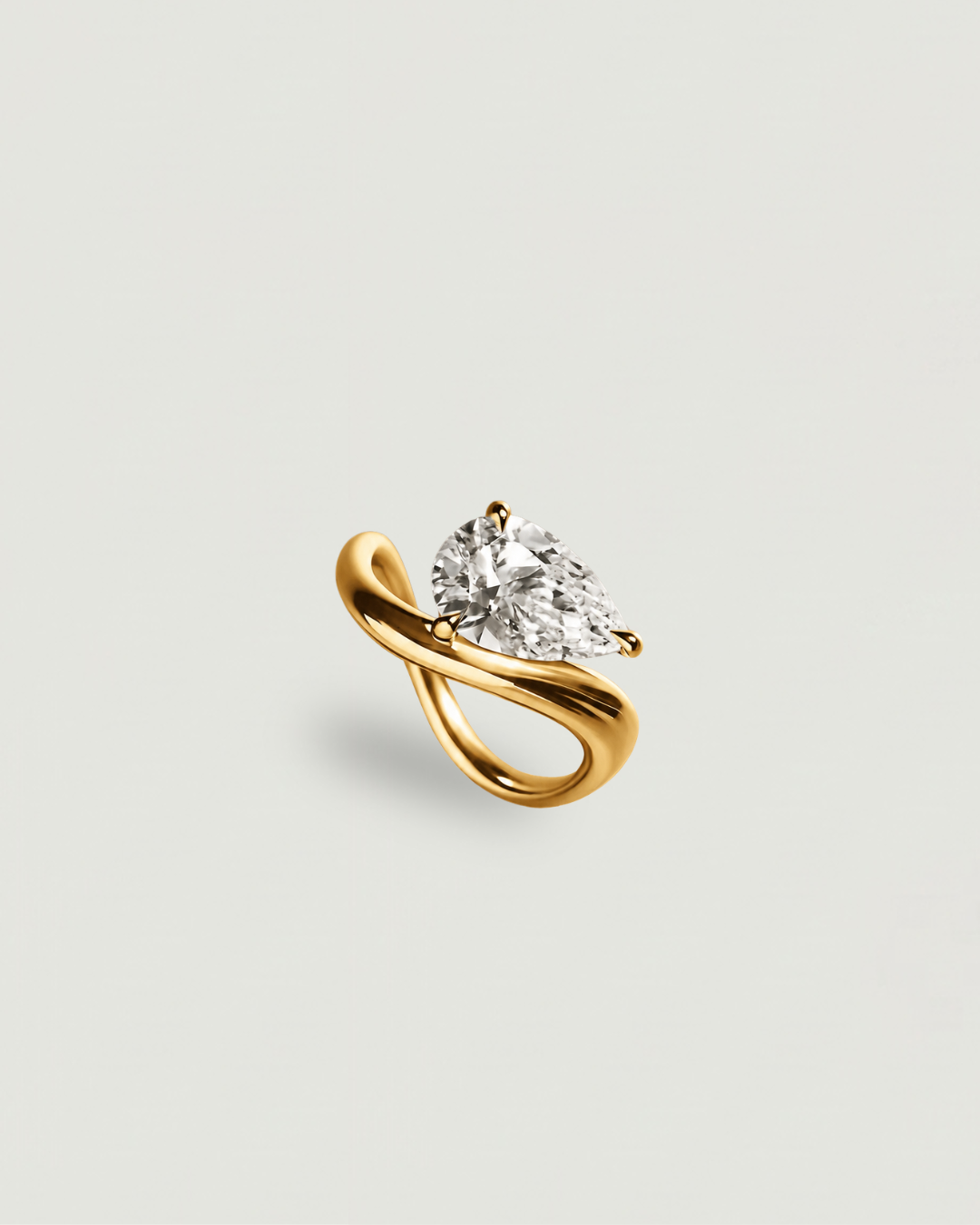 A yellow gold ring featuring a pear-cut clear gemstone in a curved, intertwined band setting, presented on a light gray background.