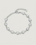 A silver chain bracelet featuring irregular, organic-shaped clear gemstones set in polished silver-toned metal, displayed on a light beige background.