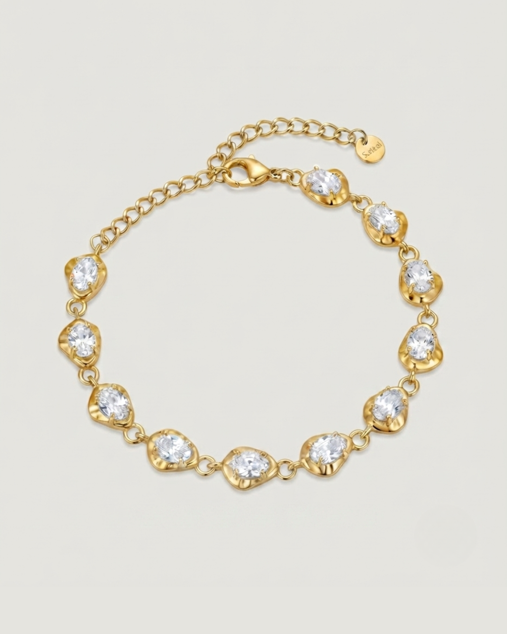 A gold chain bracelet with nine heart-shaped bezel settings containing clear round-cut stones, displayed on a light beige background.