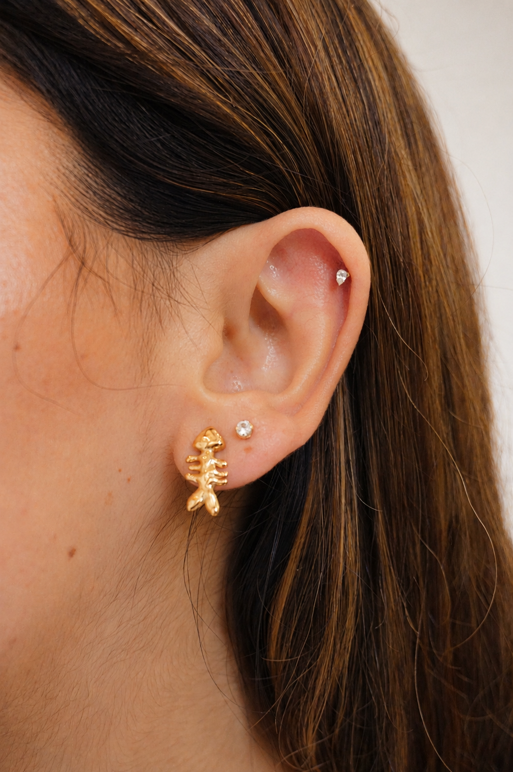 gold fish stud earring on model with brown hair