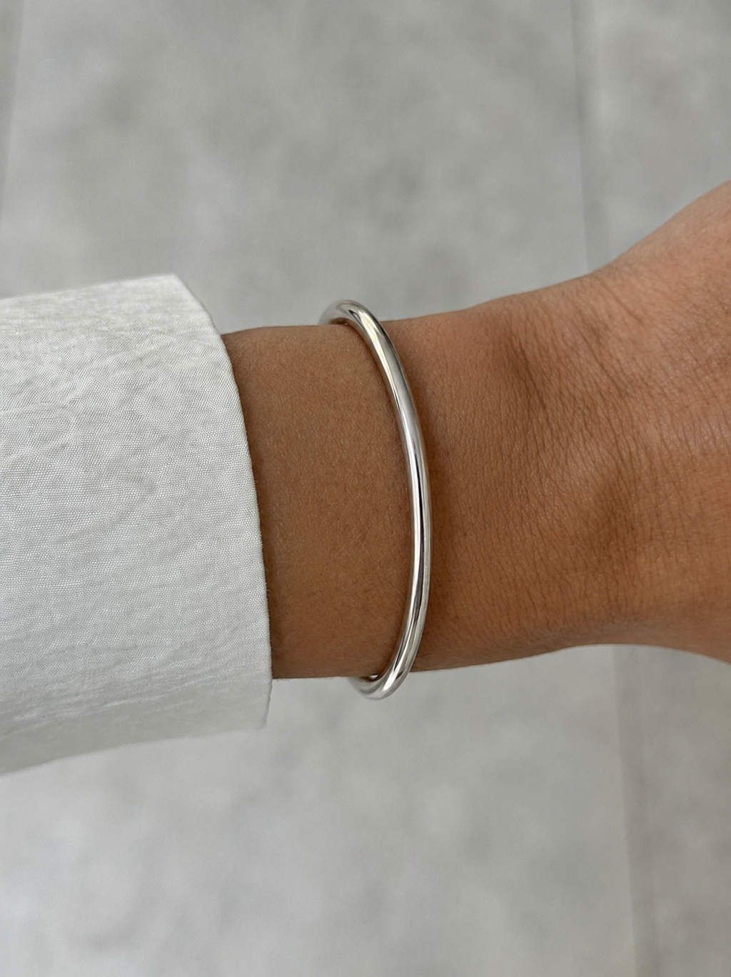 silver metal cuff on model hand with white-grey background