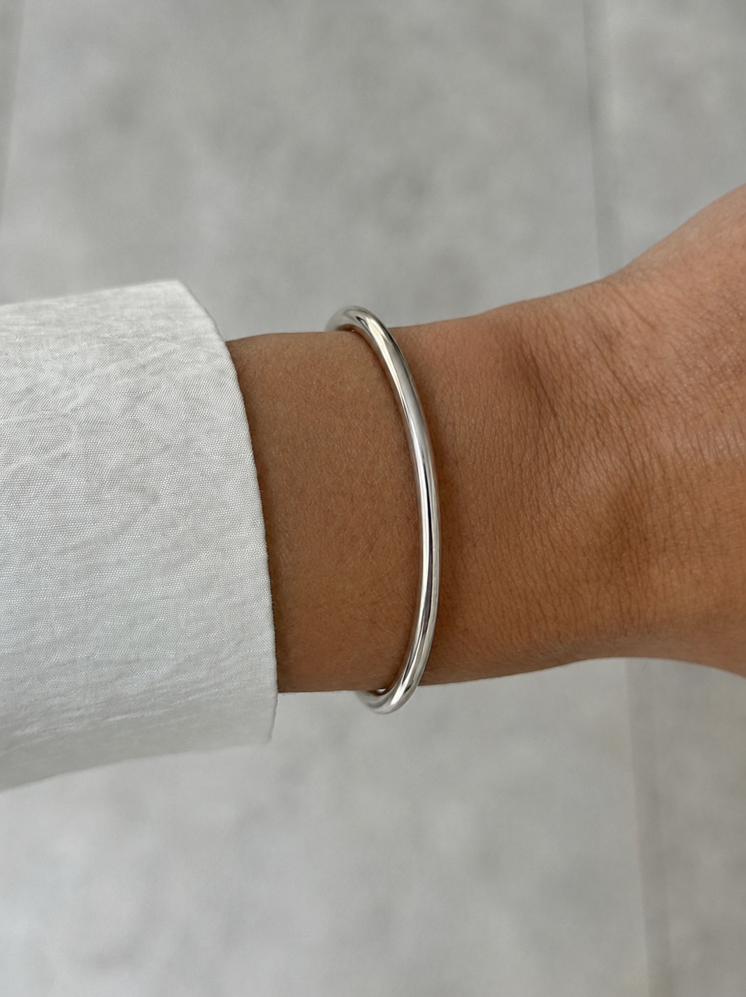 silver metal cuff on model hand with white-grey background
