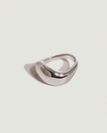 A polished silver ring with a wide, curved, boat-like silhouette, photographed on a solid light gray background with a soft shadow.